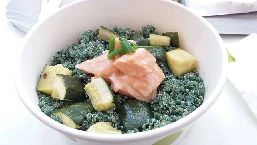 Salade de quinoa teinté à la spiruline avec courgettes et saumon dans un bol