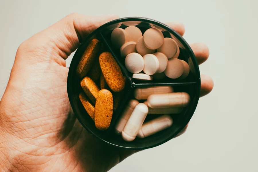 Capsules et gélules de compléments alimentaires étalées sur une surface claire
